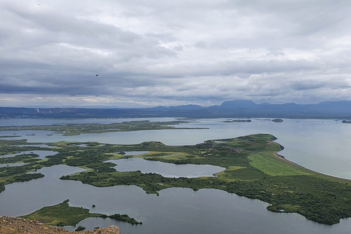 Aerial view of Lake Mývatn showing Skútustaðagígar pseudocraters as green islands and far mountains.