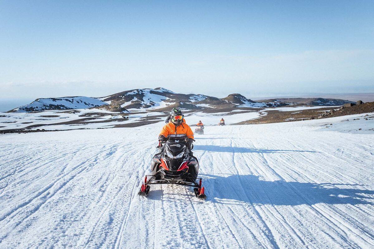 Snowmobile riders following a track across Eyjafjallajökull glacier in South Iceland. 