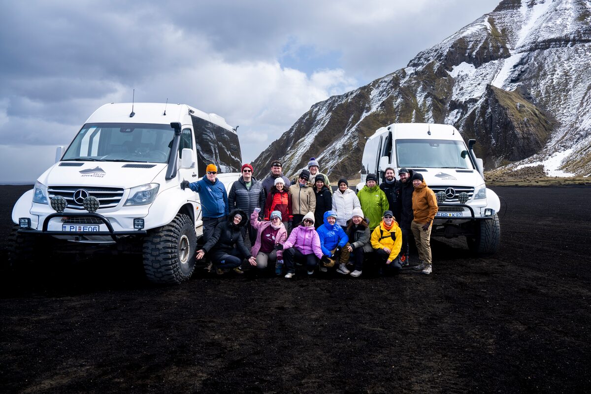 Arctic Adventures FAM trip group with two super jeeps on black volcanic sand, South Iceland.