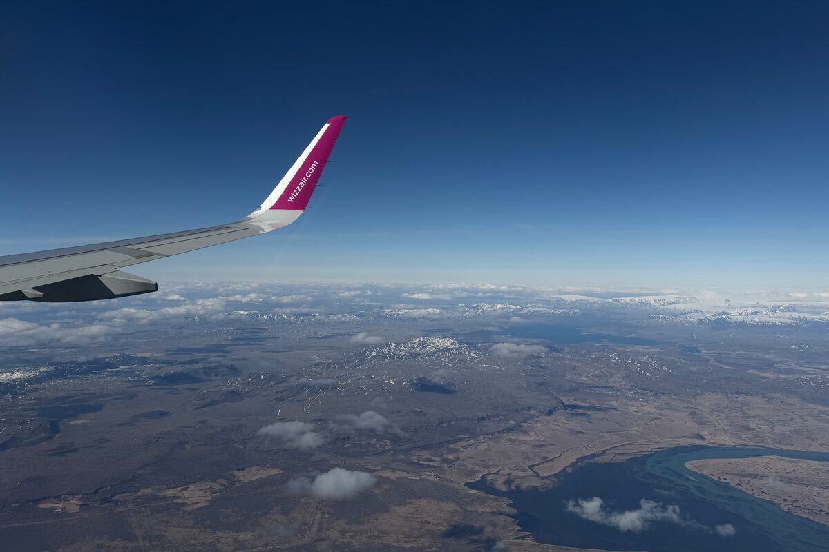 Wizz Air winglet with snow-patched Icelandic terrain and coastline below
