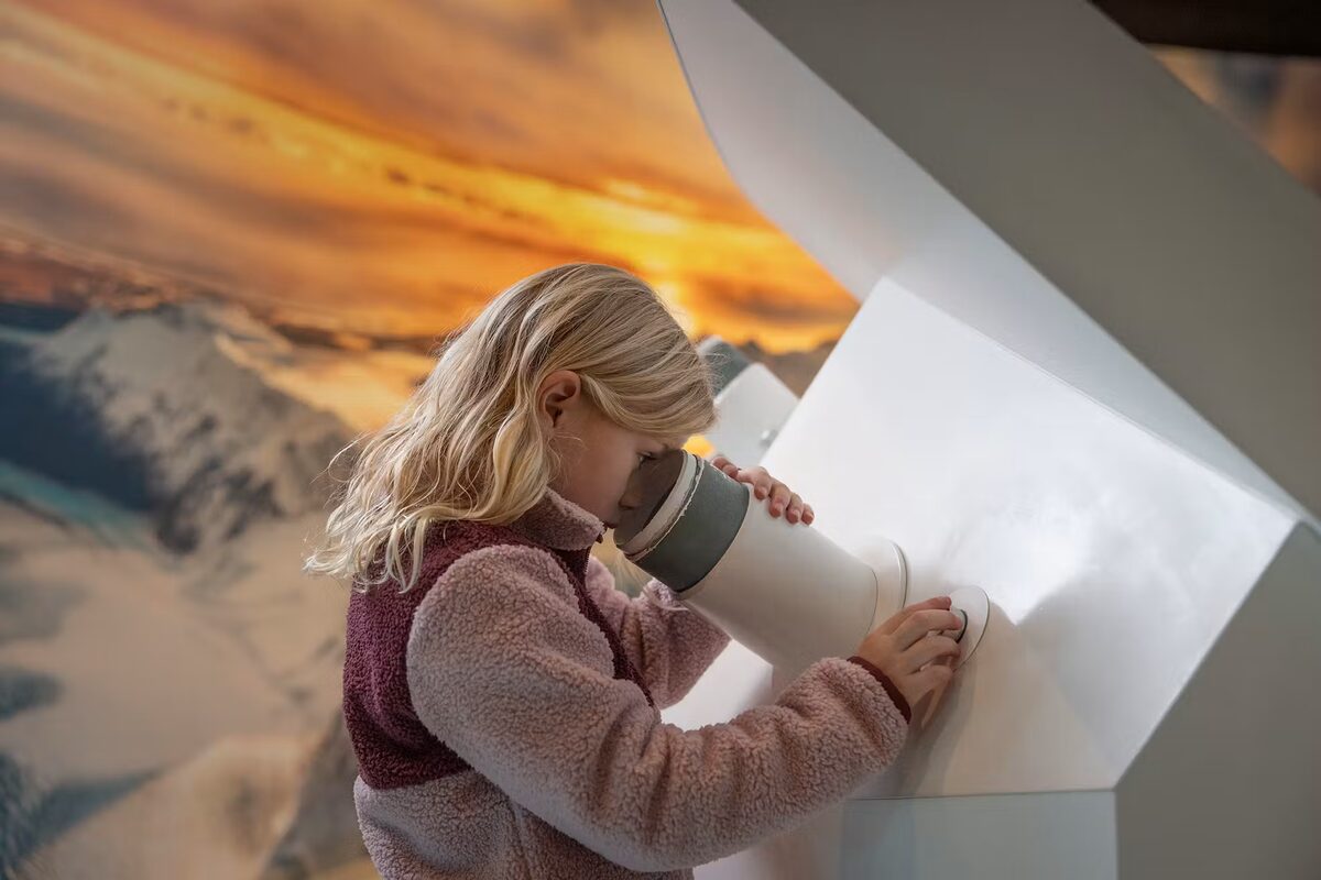 Girl Looking Into A Scope At Perlan in Iceland
