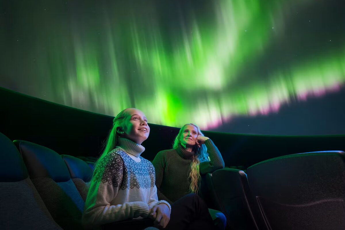 Mom And Daughter Looking Up At Northern Lights At Perlan in Iceland