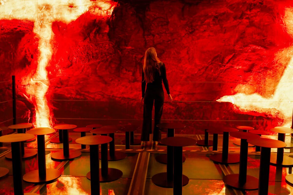 Woman At Perlan Looking At A Screen Showing Volcano Eruption in Iceland