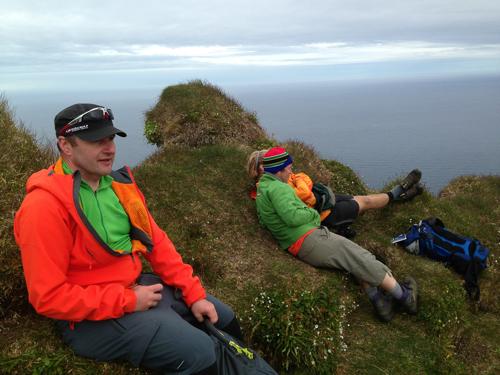 Hikers Relaxing On Grass Cliff in Iceland