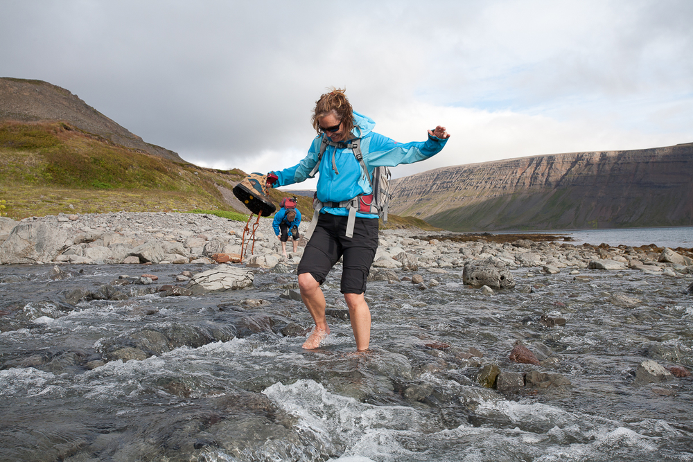 Woman On A Hike In Water Holding Her Shoes in Iceland