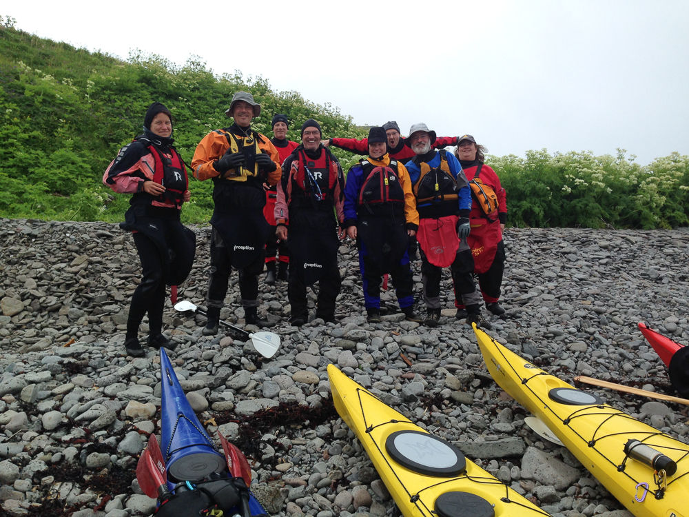 Group Of People Posing For A Picture With Kayaks On The Rocky Ground in Iceland