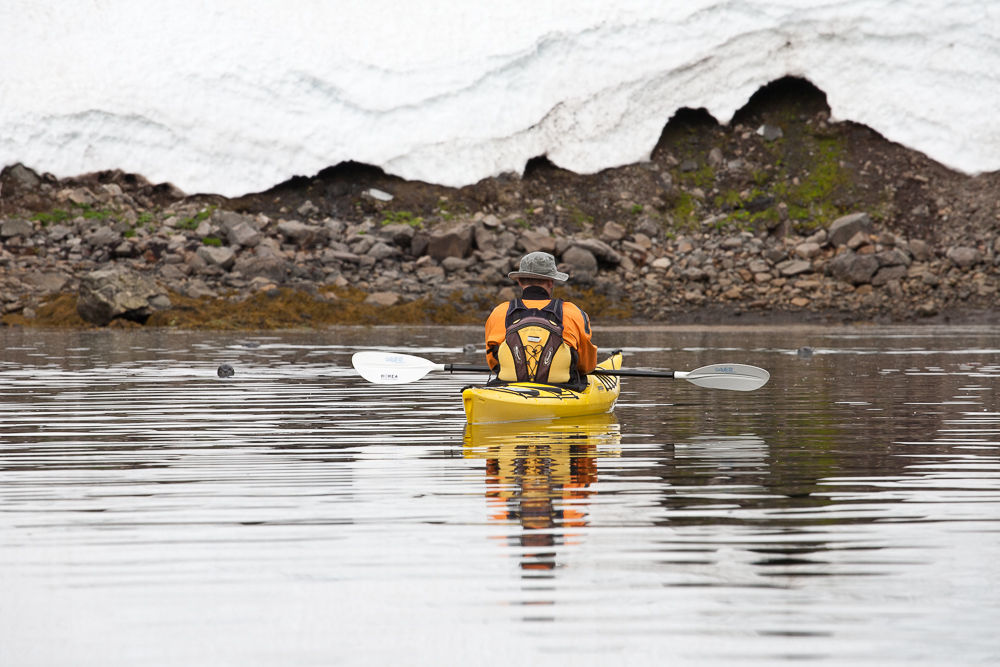 Man In A Yellow Kayak With A Rocky Shore In The Background in Iceland