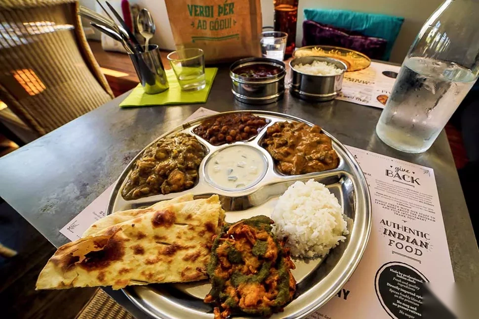 Indian thali at Hraðlestin restaurant with chickpea curry, creamy curry, naan, pakora, rice, and raita.