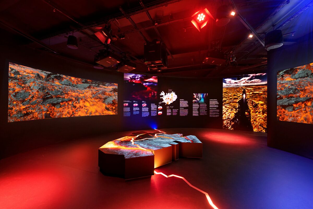 Immersive volcano exhibit at Perlan with curved lava screens and a glowing floor model of Iceland.