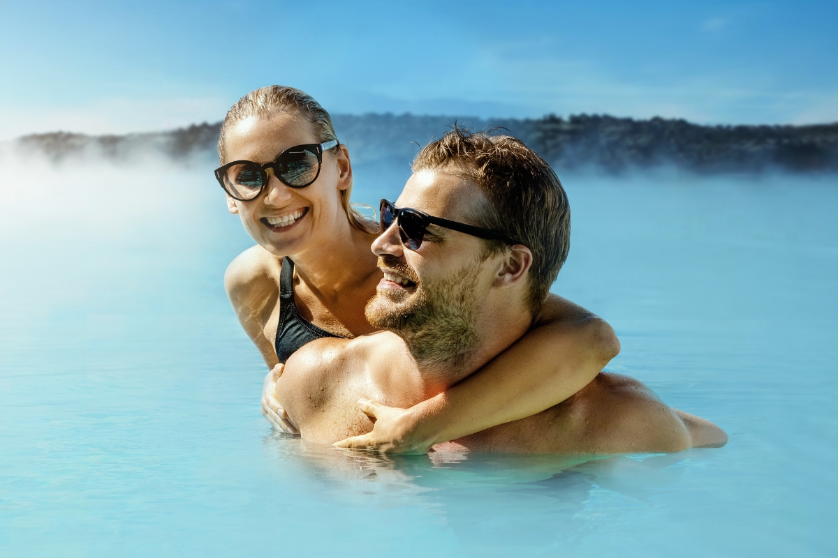 Couple soaking in the Blue Lagoon at sunset, warm light over the geothermal water.