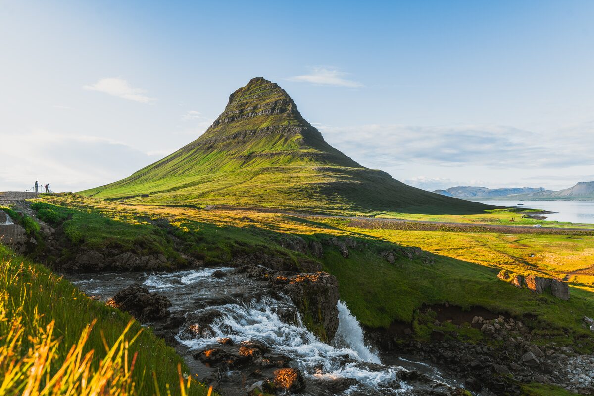 Kirkjufell mountain in West Iceland with the Kirkjufellsfoss waterfall in the foreground at golden hour.