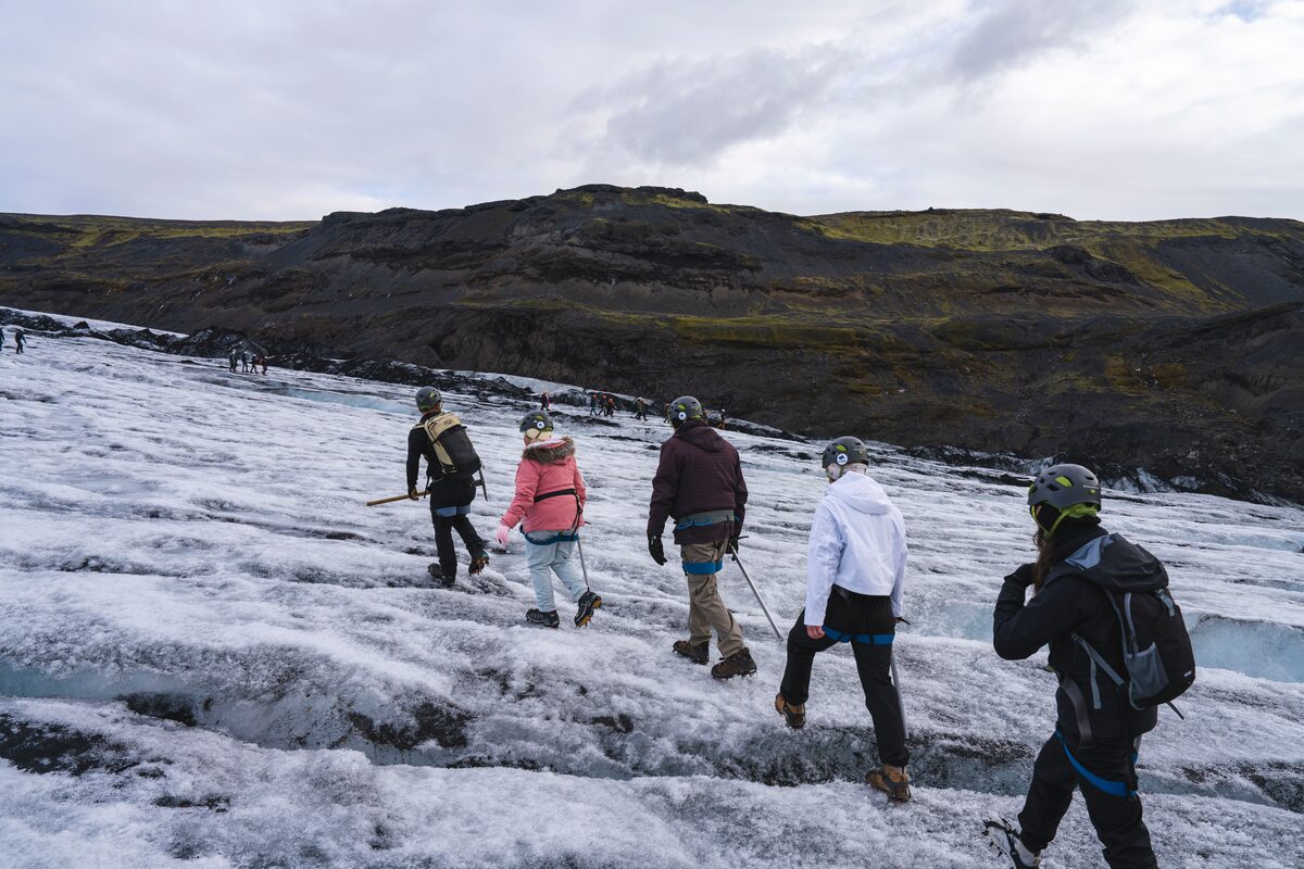 Group of hikers in crampons walking up Sólheimajökull glacier in South Iceland, guide in front.