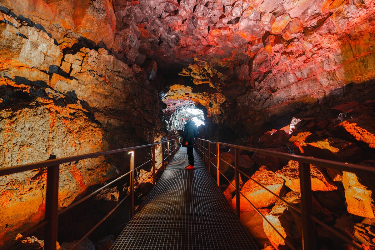 Visitor with a headlamp on a steel walkway inside the lava tube Raufarhólshellir