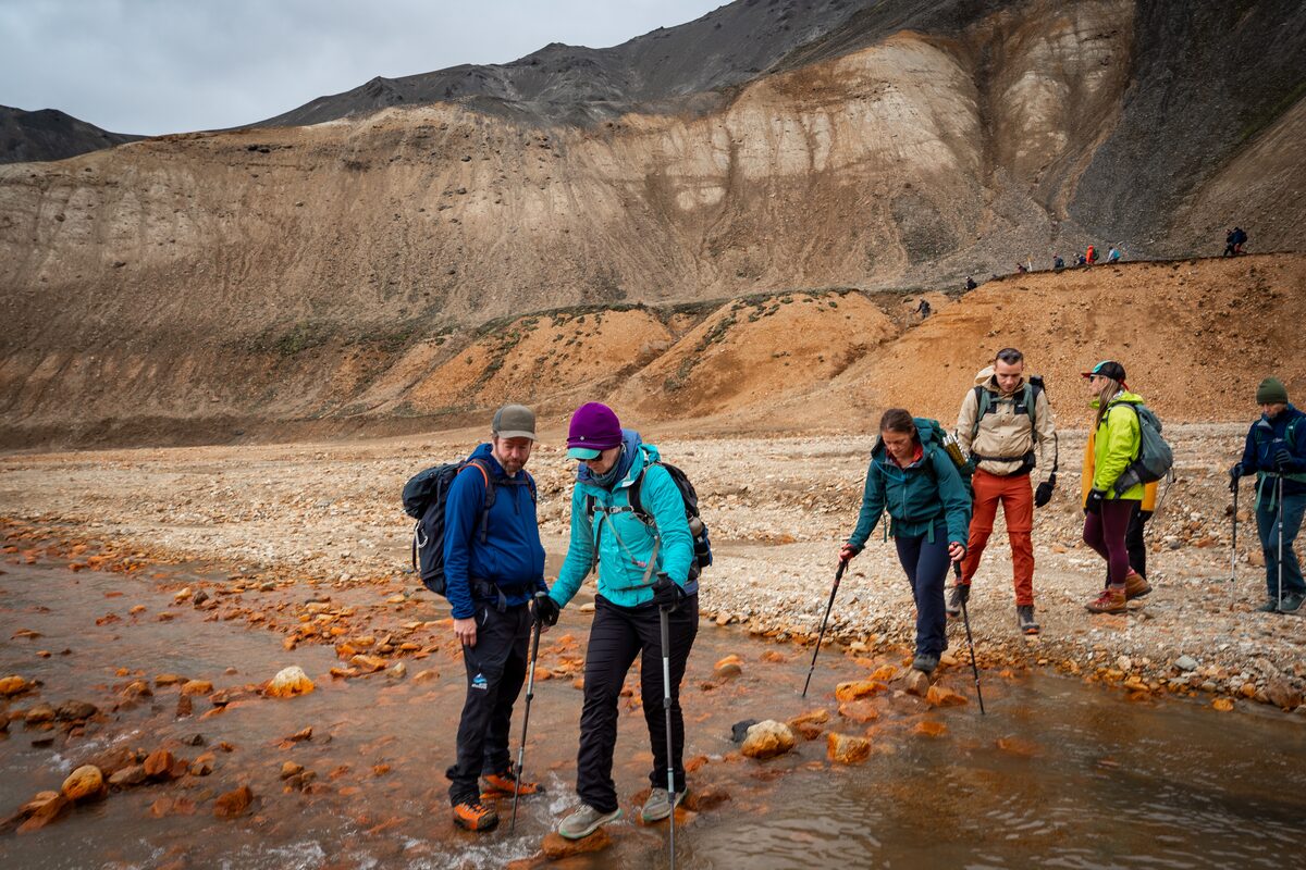 Hikers in waterproof layers crossing changing weather conditions in the Icelandic highlands.