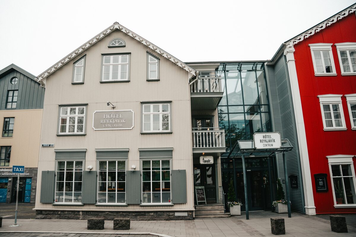 Hótel Reykjavík Centrum, a cream timber building beside red and gray houses in Reykjavík.