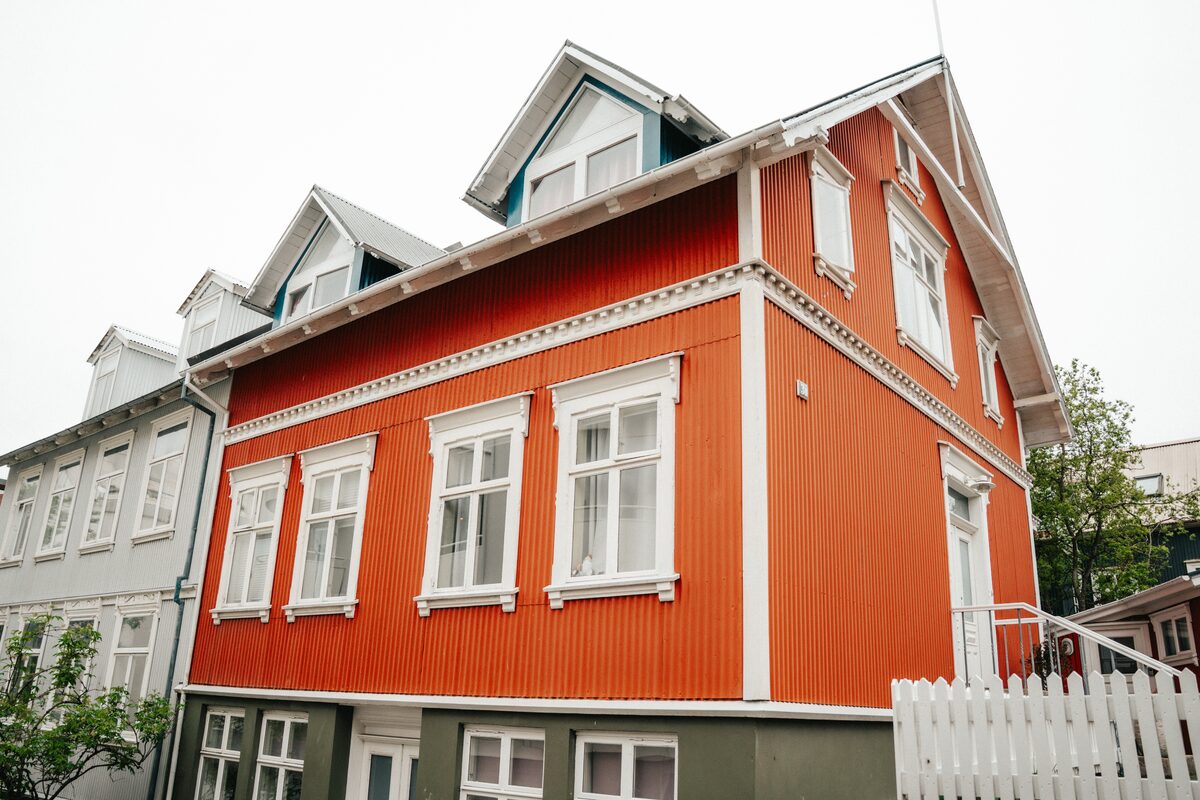 Orange corrugated-iron house with white windows on a street in central Reykjavík.