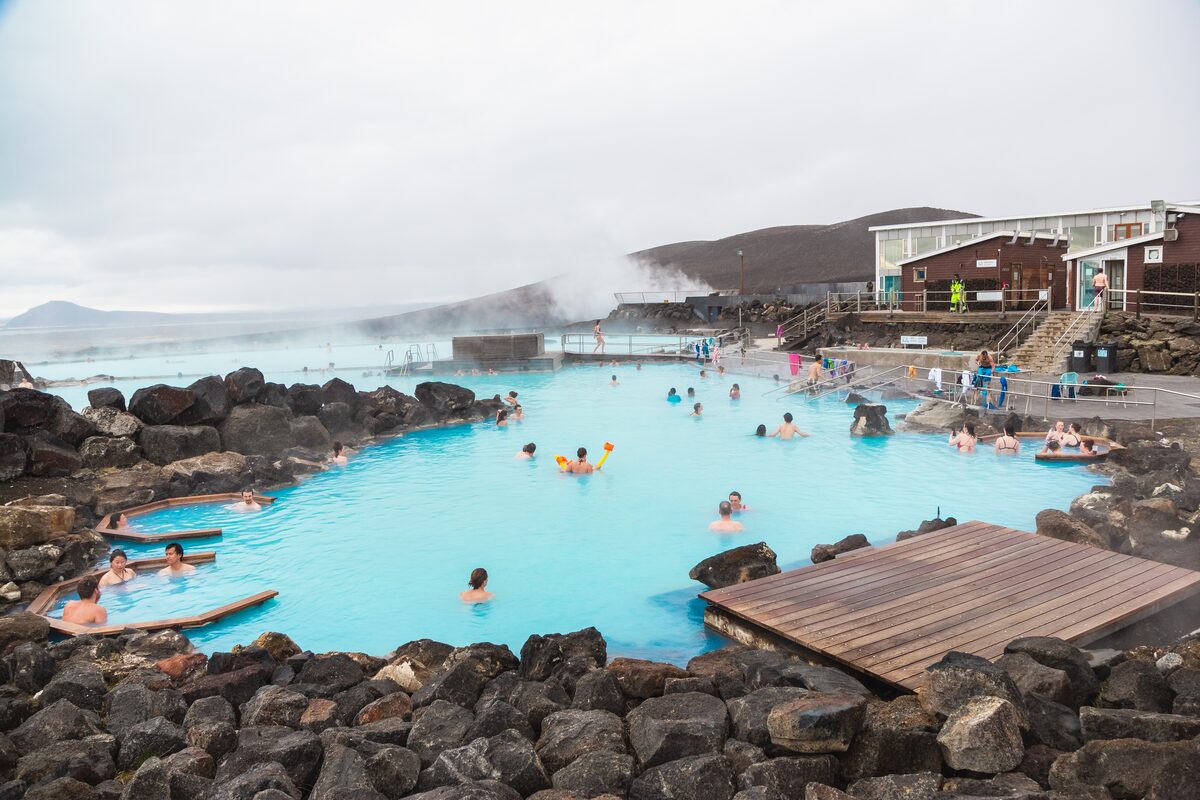 Bathers in the milky-blue lagoon at Mývatn Nature Baths, ringed by black volcanic rock.