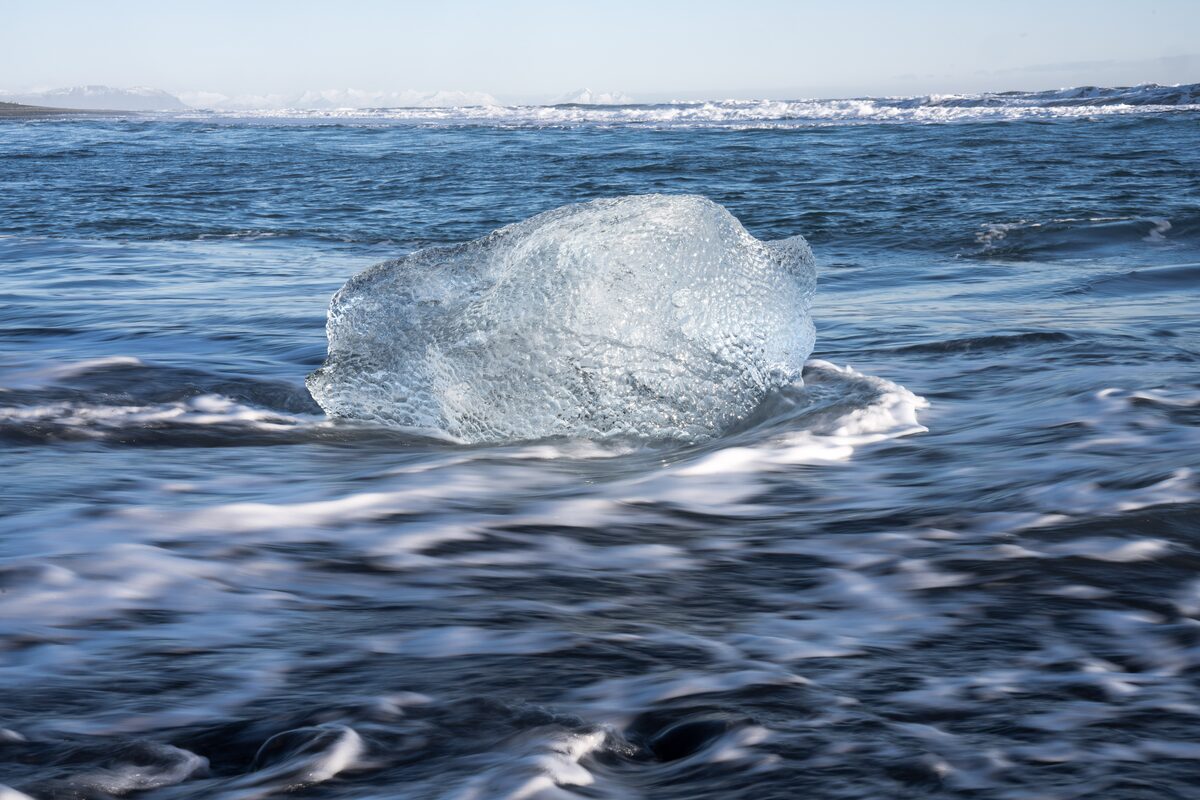 Long-exposure waves blurring around glacier ice on the Diamond Beach.