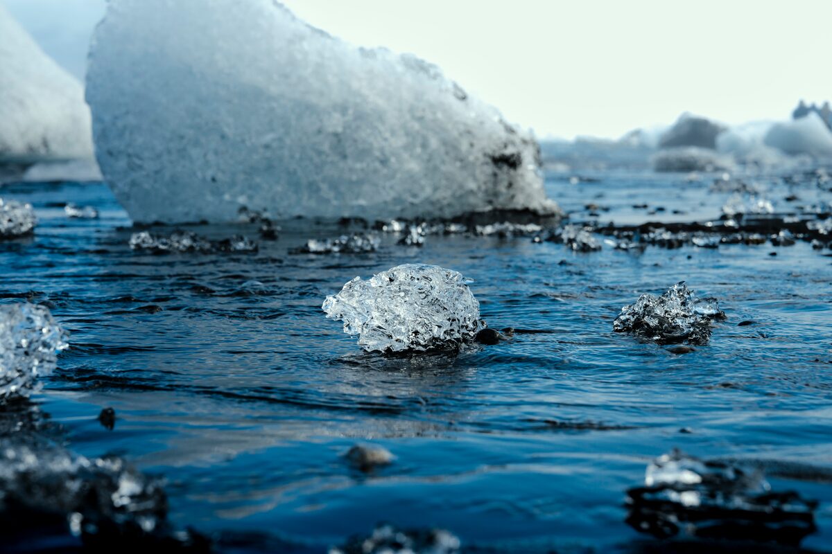 Low-angle shot of a clear ice block on wet black sand.