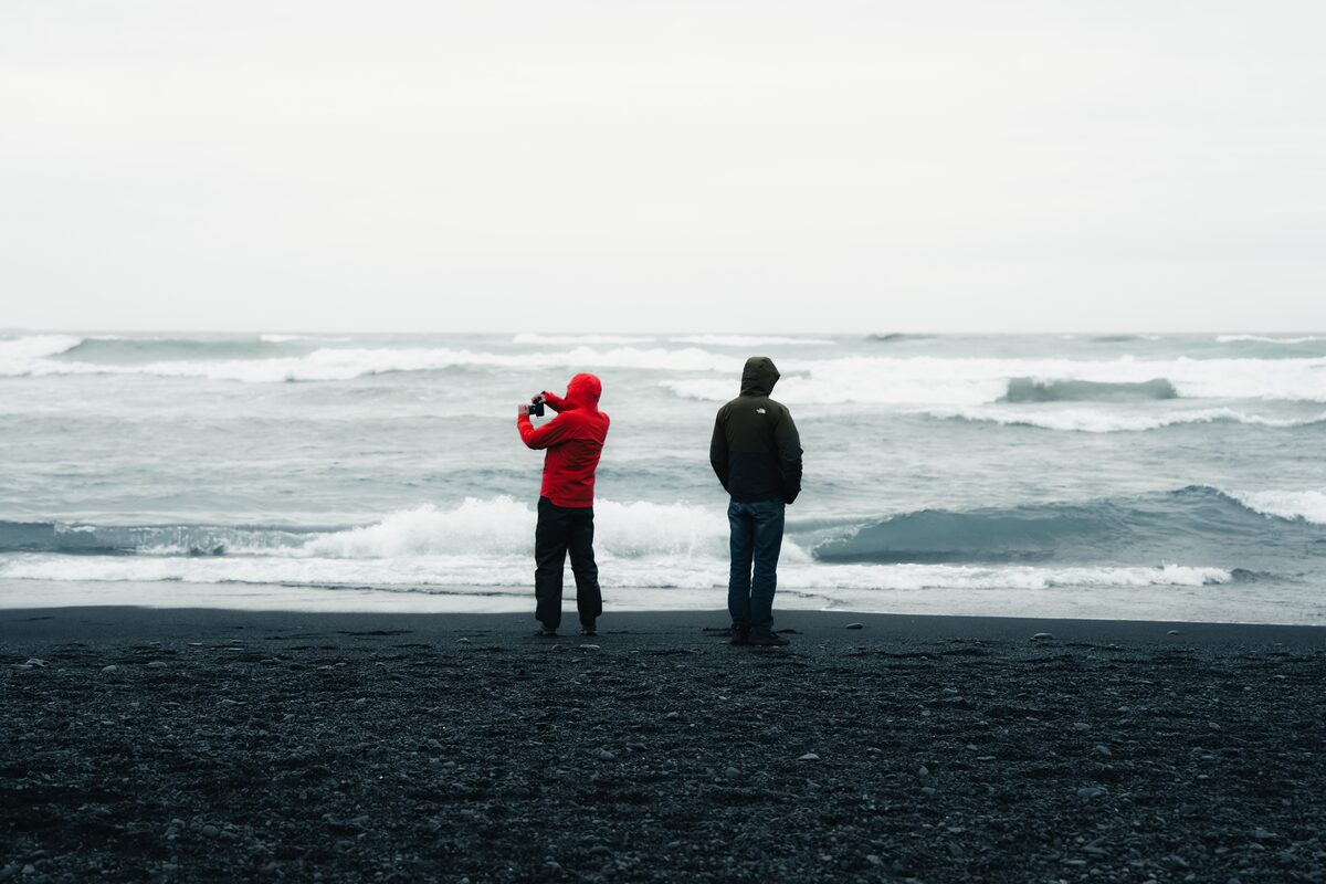 Photographer wiping salt spray from a lens at the shoreline.