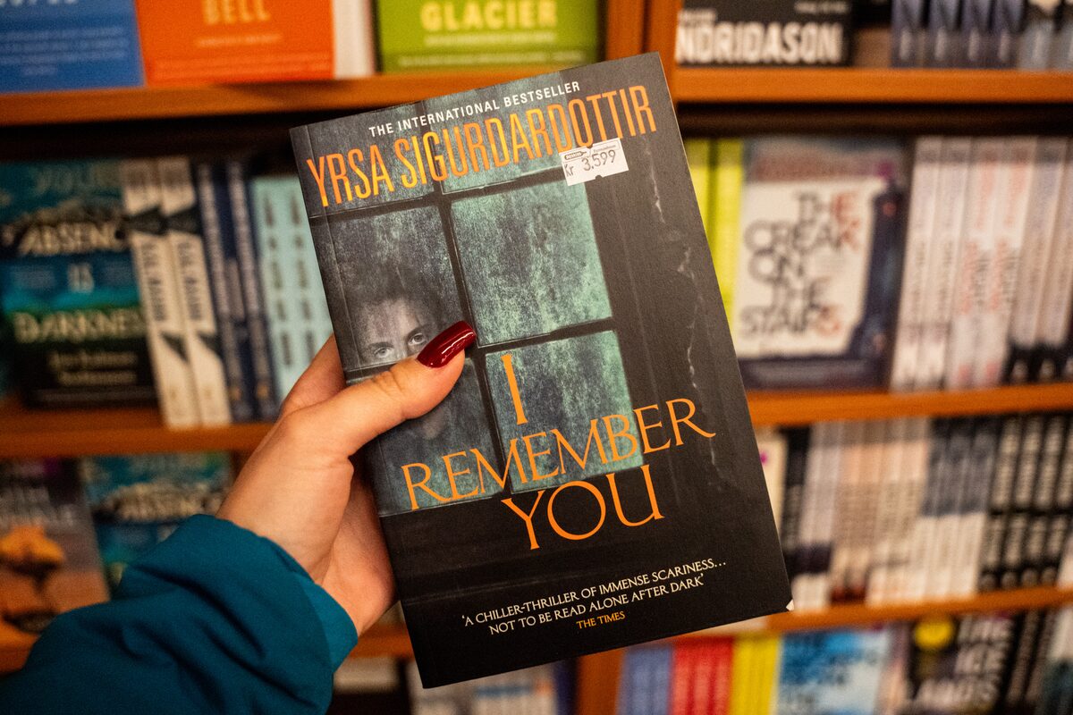 Hand holding the book I Remember You by Yrsa Sigurðardóttir in a bookstore.