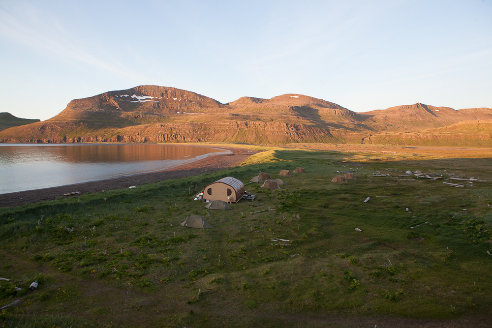 Built Tents Near Water With Hills In The Background in Iceland