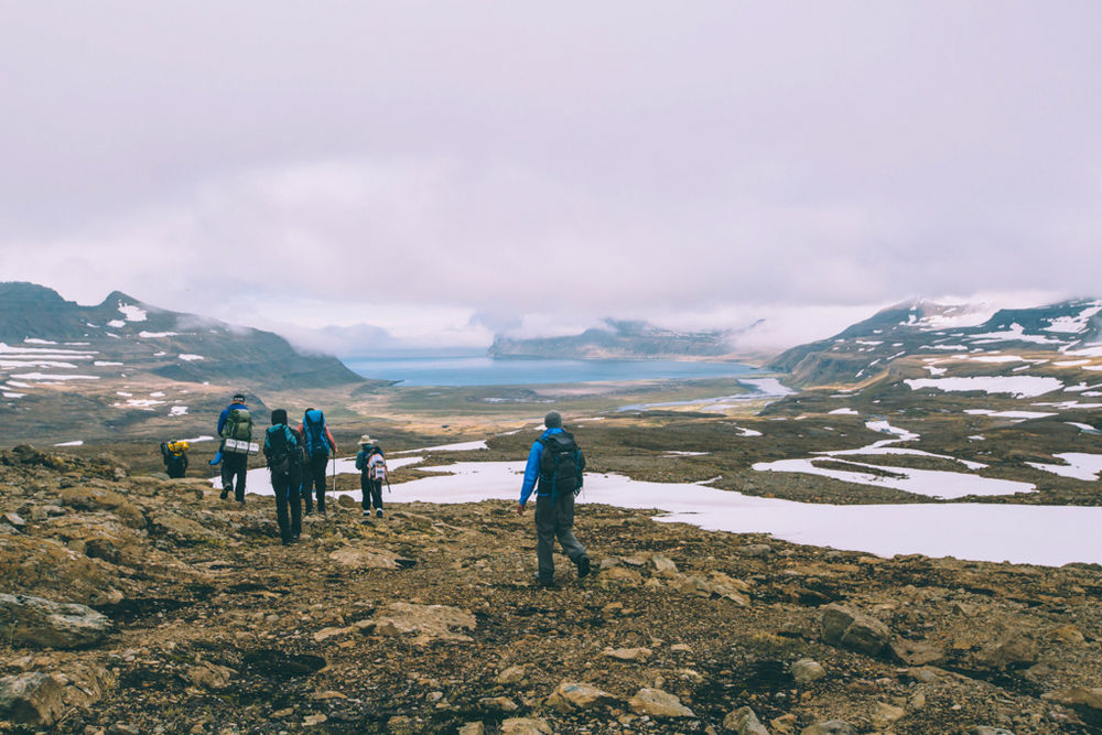 Hiker Group Walking Through Hills With A Cloudy Sky in Iceland