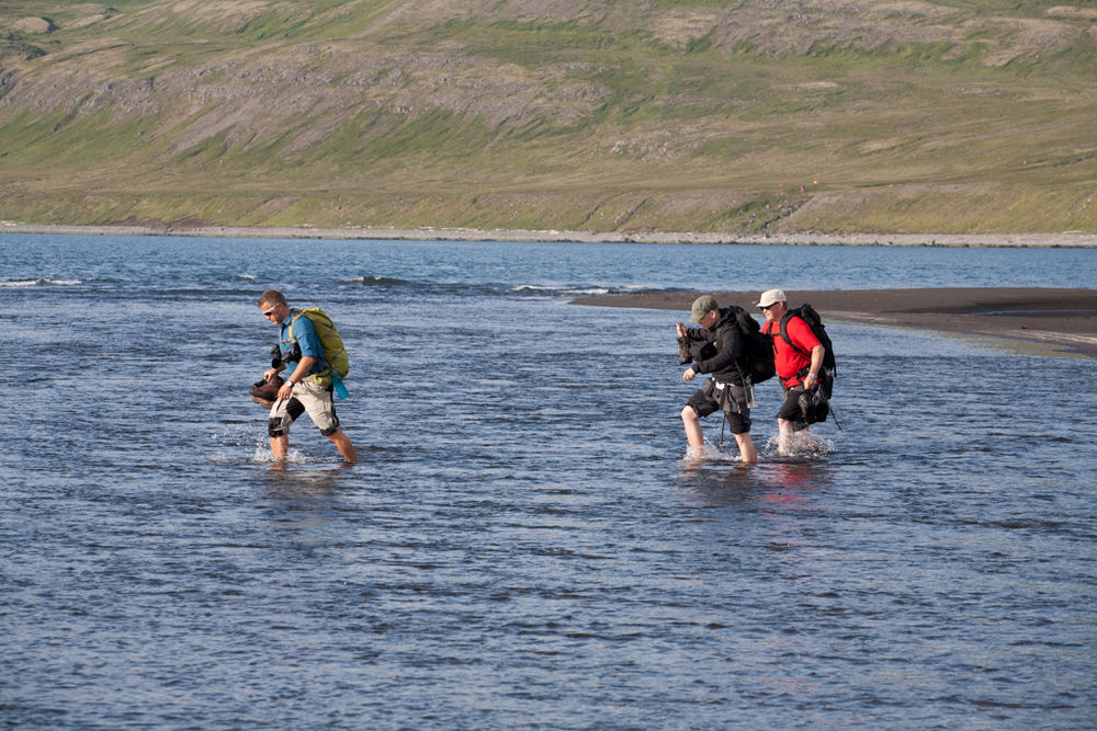 Three Hikers Wading Through Water in Iceland