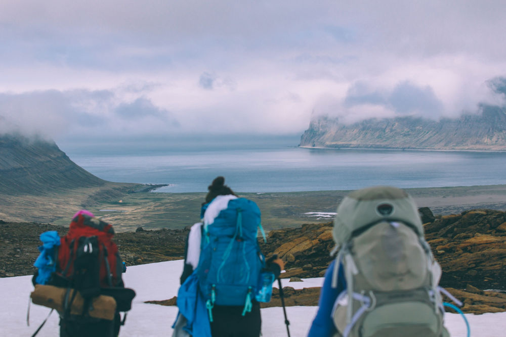 Three Hikers With Sea Shore And Clouds In The Background in Iceland