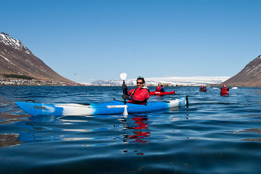 Kayaks Between Mountains With Town In The Background in Iceland