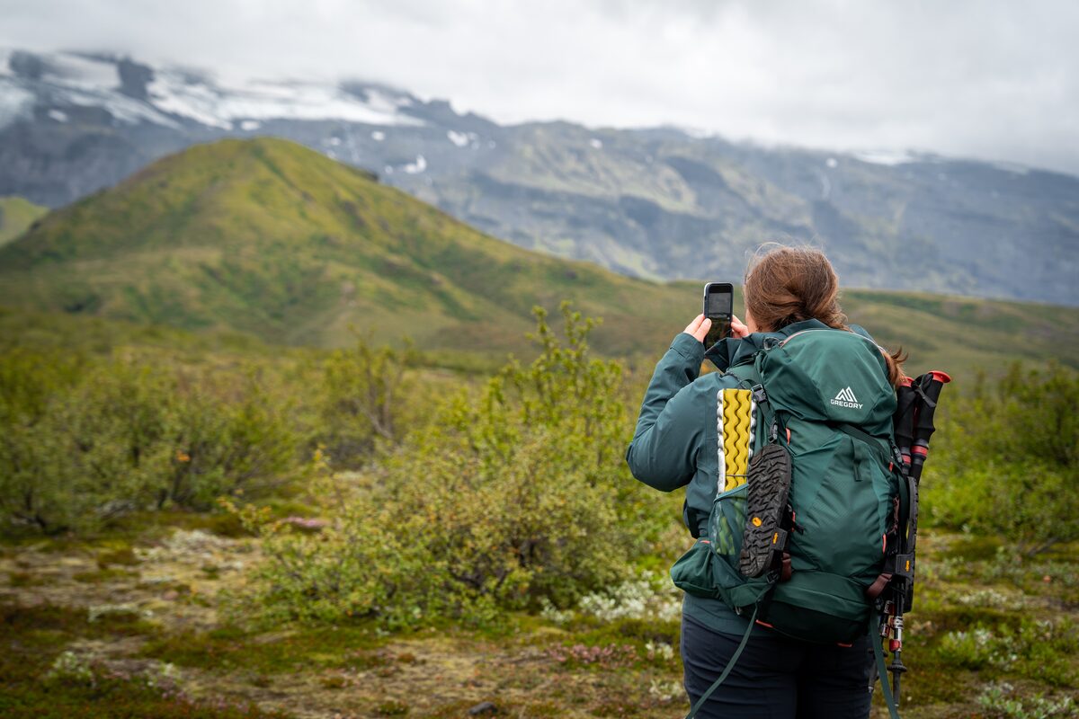 Solo traveler walking a marked trail in the Icelandic highlands on a clear day.
