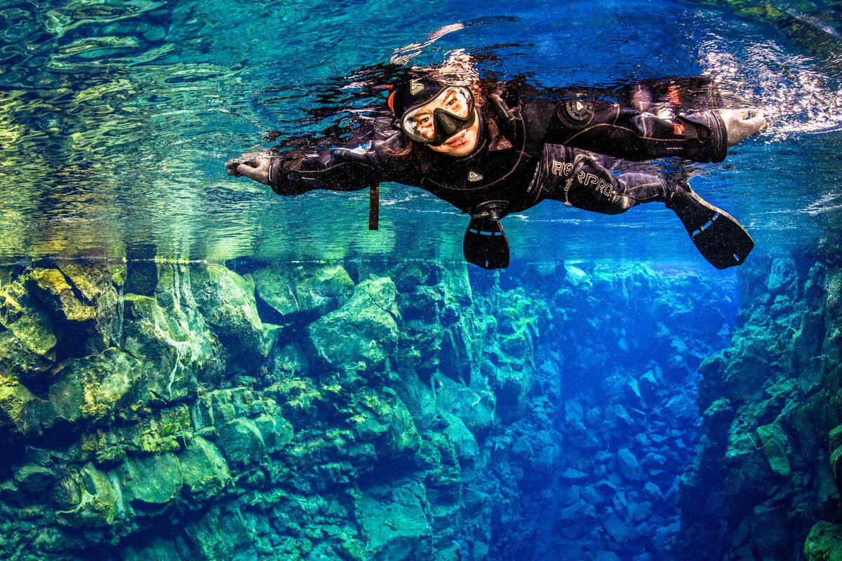 Snorkeler floating in the clear blue water of the Silfra fissure in Iceland.