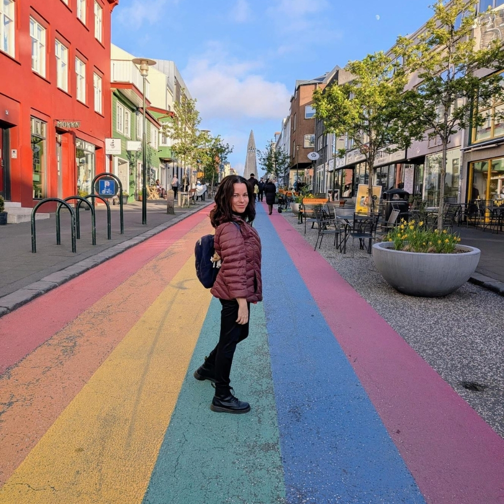 Eva on Reykjavík's Rainbow Street with Hallgrímskirkja church in the background.