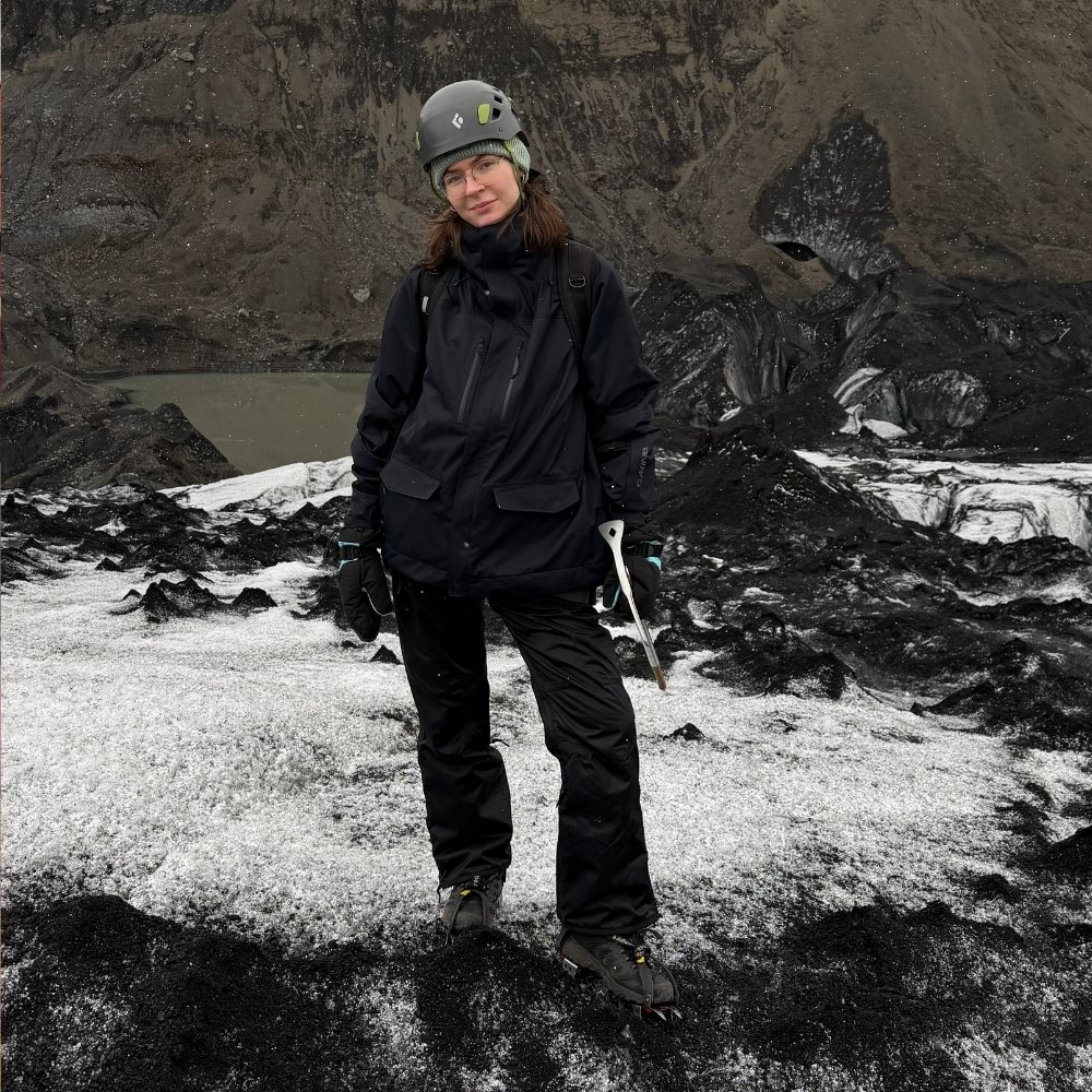 Justyna on Sólheimajökull glacier in Iceland, wearing a helmet and harness with an ice axe.