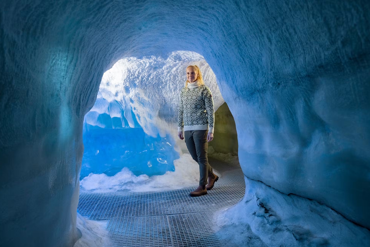 Image of female traveler wearing Icelandic wool sweater, exploring glacier ice tunnel.