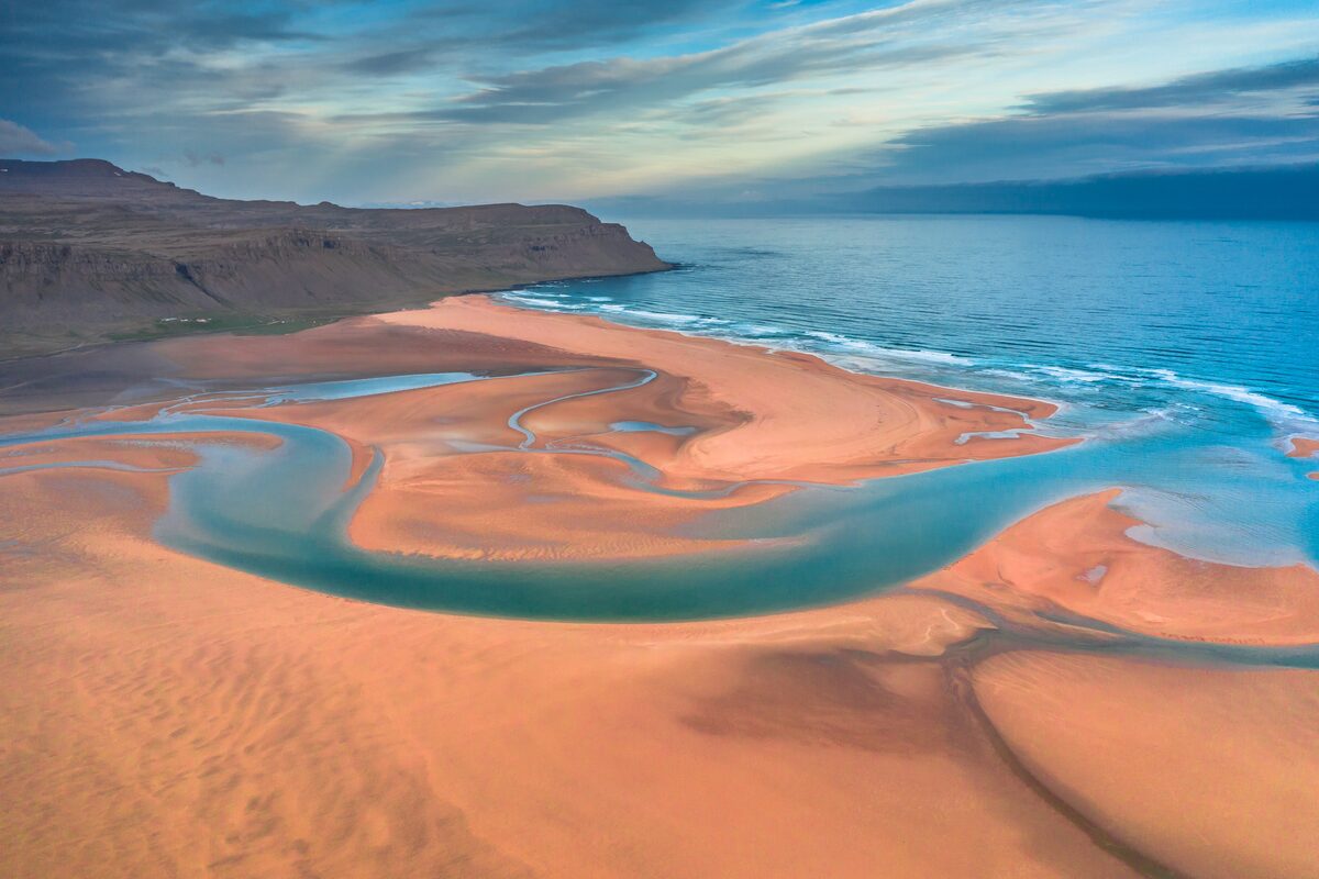 Aerial view of golden sand and turquoise tidal channels at a beach on Iceland's Westfjords coast.