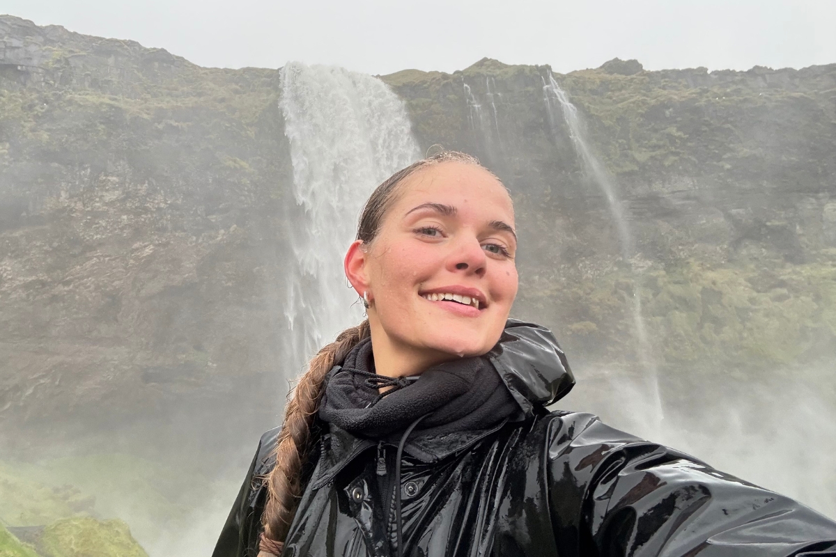 Anhelina Zhaliazka, Content Lead at Arctic Adventures, in front of Seljalandsfoss waterfall in South Iceland.