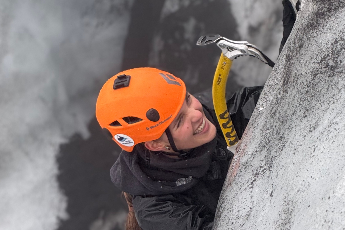 Anhelina is ice climbing on Sólheimajökull, gripping yellow ice axes against the blue-grey glacier ice.