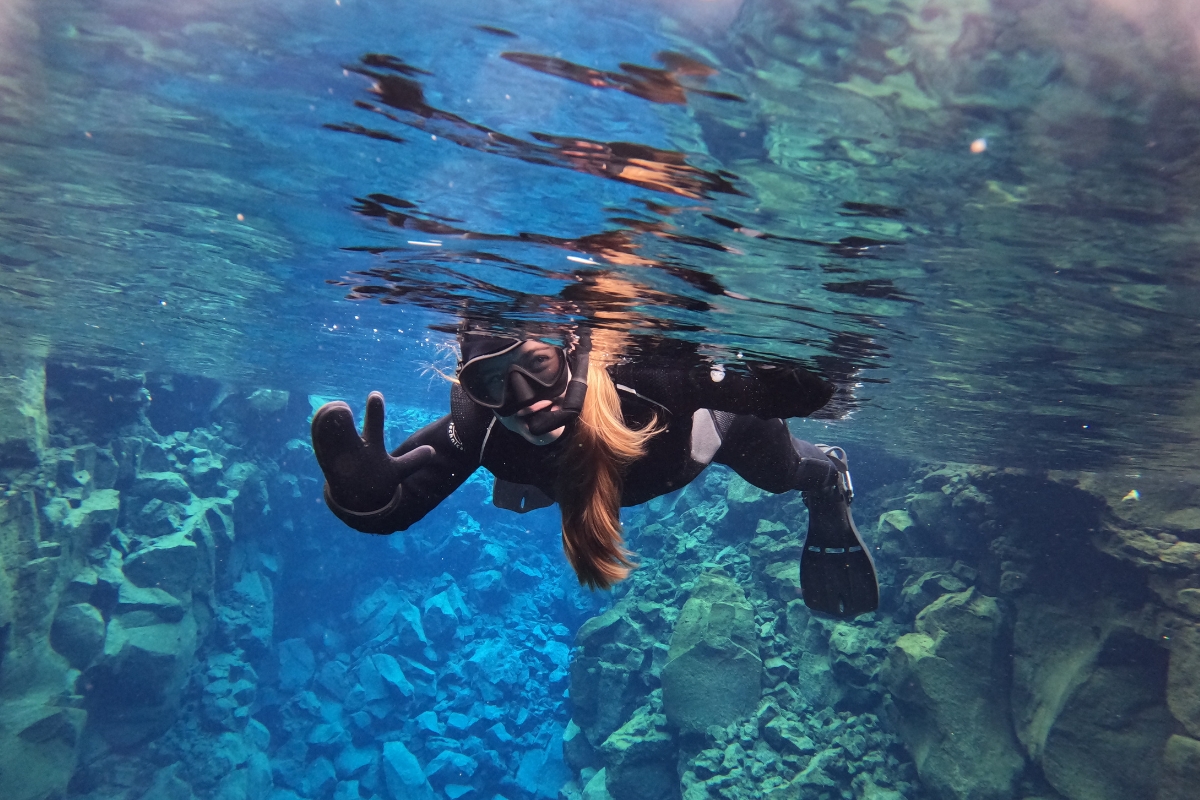 Anhelina Zhaliazka, Content Lead at Arctic Adventures, snorkeling in the clear water of the Silfra fissure.