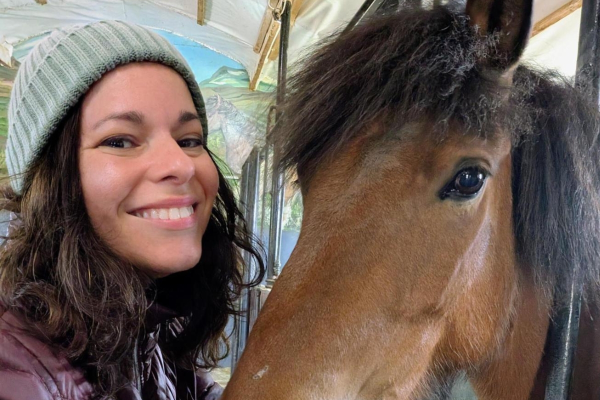 Eva Sadler beside a brown Icelandic horse in the stable at Sturlureykir horse farm, on the Silver Circle route in West Iceland.