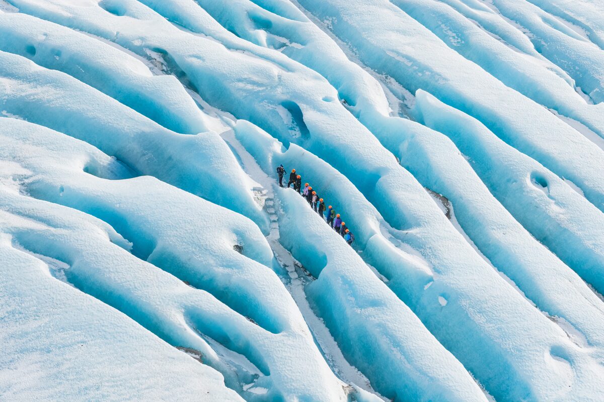 Aerial shot of blue ice crevasses and group looking small