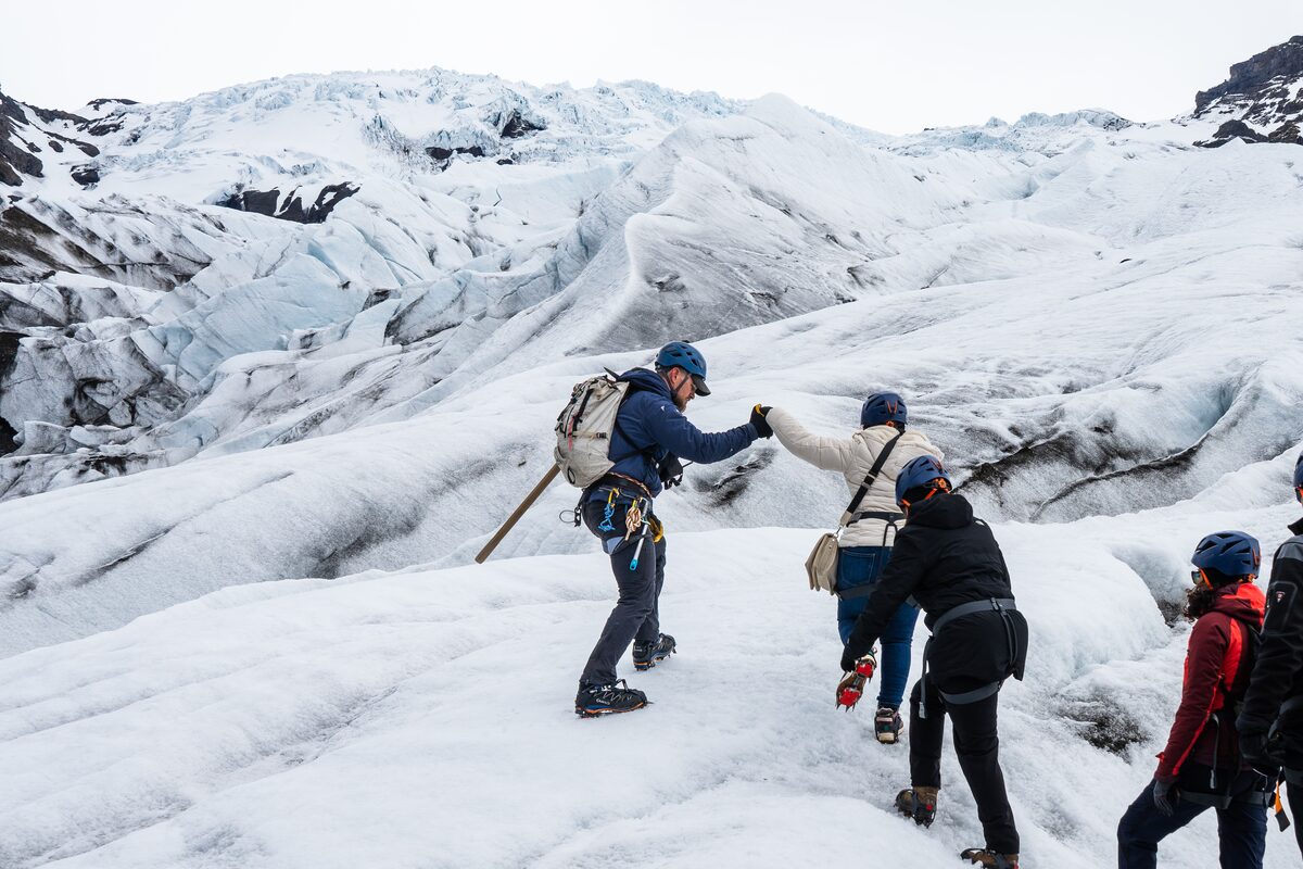 Guide Helping Tourists Get On The Glacier in Iceland