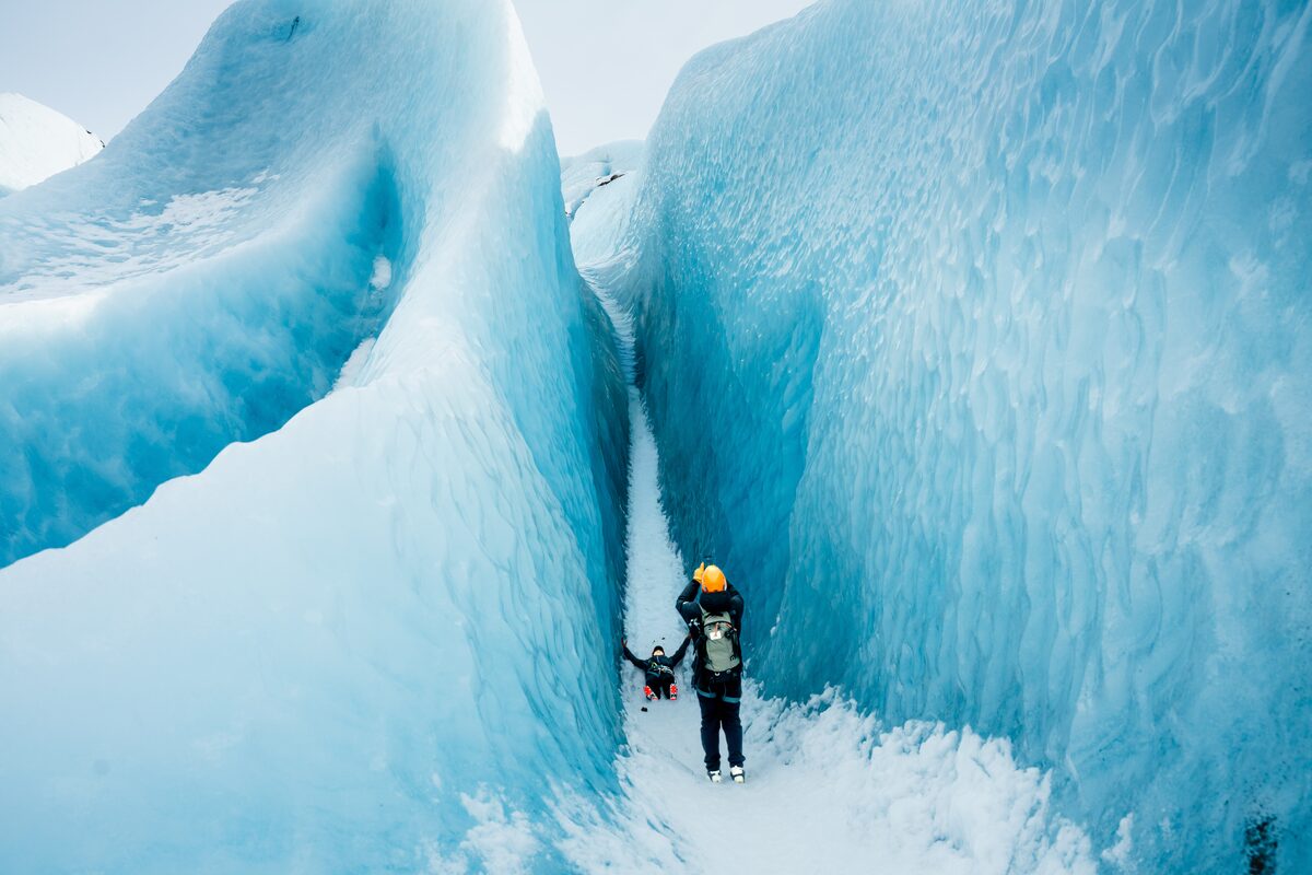 Person Laying Down In A Glacier Crevasse With Another Person Taking A Picture in Iceland