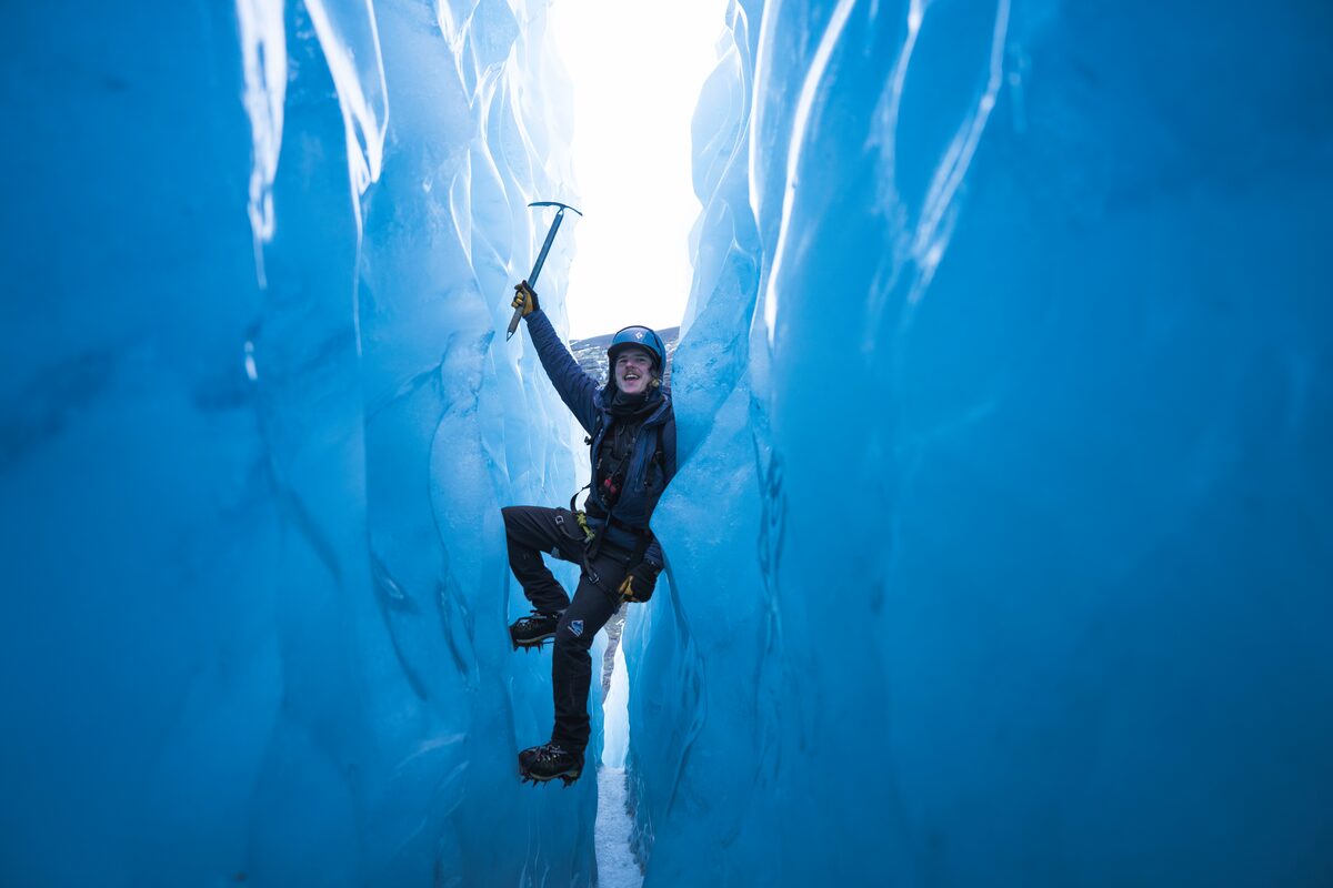 Guest holding ice axe surrounded by dark blue ice