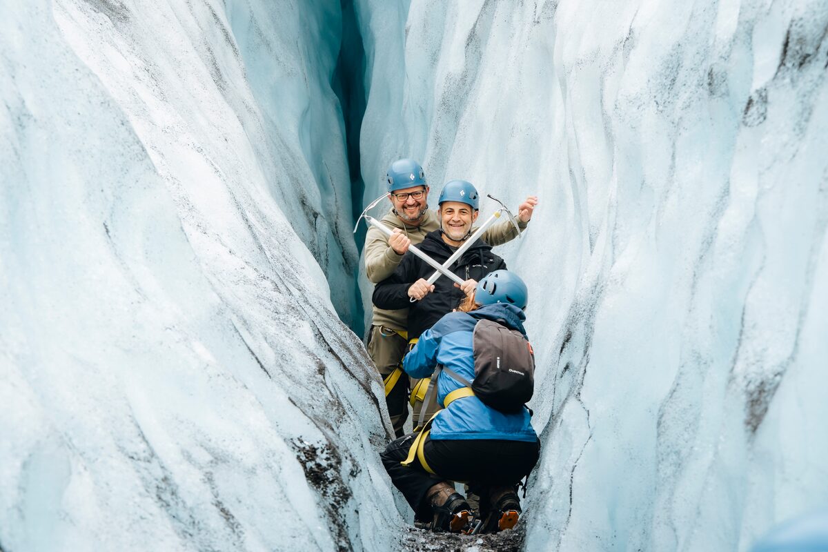 Two Men With Pickaxes Crossed Posing For A Picture With A Another Person Taking The Picture in Iceland