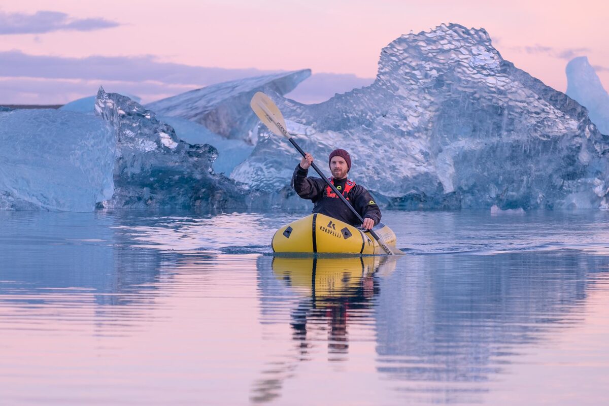 Man In A Yellow Kayak Rowing With Ice Formation In The Background in Iceland