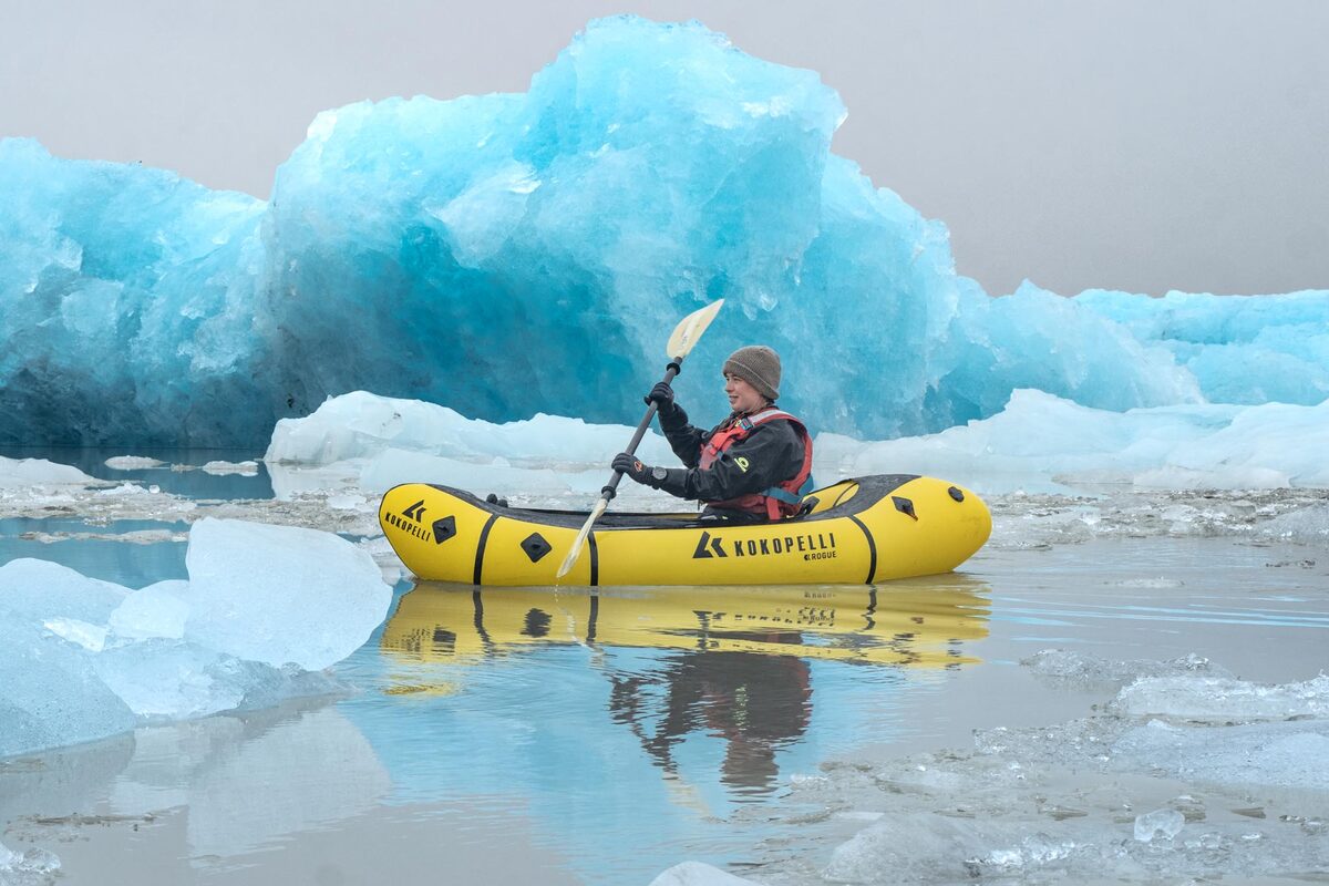 Yellow Kayak And A Big Iceberg In The Background At Fjallsarlon Glacier Lagoon in Iceland