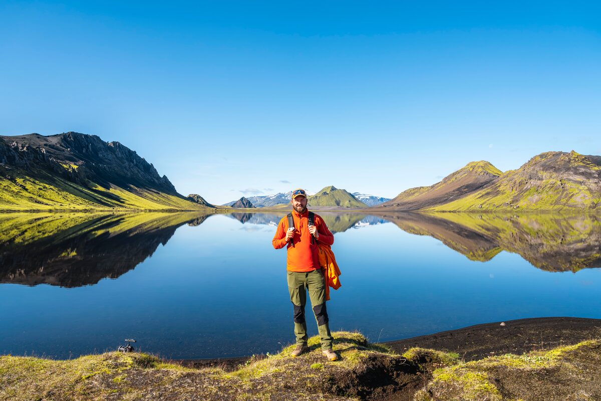Man In An Orange Sweater Near Water With Mountains Around in Iceland