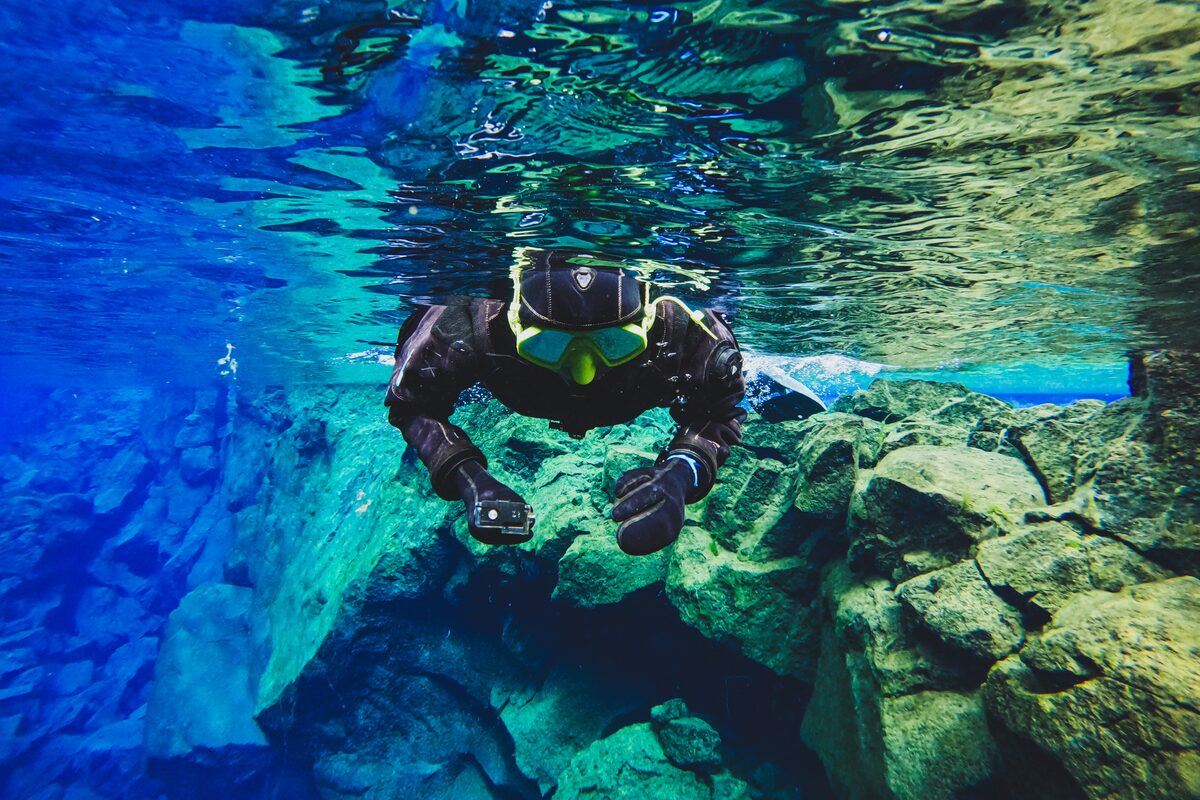 Person With Full Snorkeling Gear Holding A Gopro Underwater in Iceland