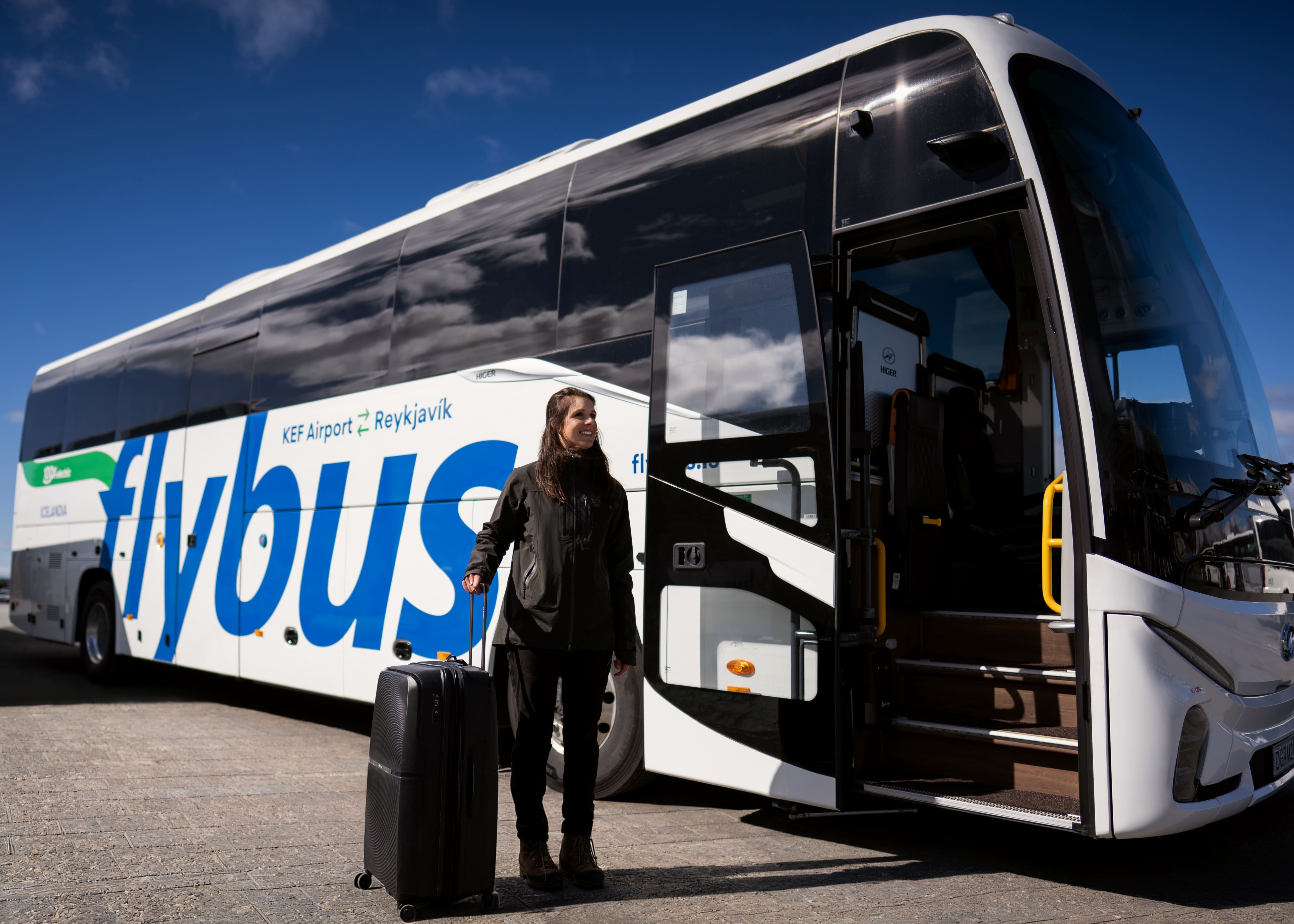 Woman With Her Luggage Stangind Next To A Flybus Bus in Iceland